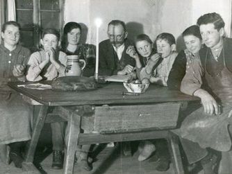 Eine historische Aufnahme aus dem Volkskundearchiv Dr. Ernst Burgstaller gibt Einblick in den Weihnachtsabend in einfachen, bäuerlichen Verhältnissen um 1935. Von 6 Uhr abends bis zum nächsten Morgen brannte hier die Mettenkerze, in deren Schein das Weihnachtsevangelium gelesen wurde.